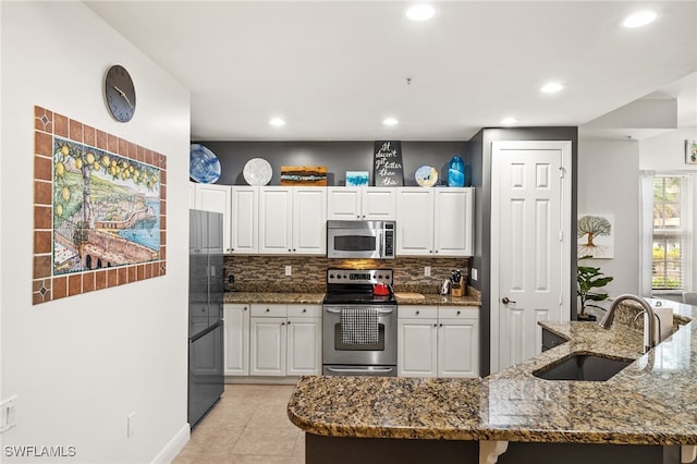 kitchen featuring white cabinets, appliances with stainless steel finishes, sink, and dark stone countertops