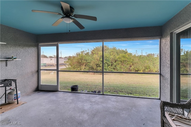 unfurnished sunroom featuring ceiling fan