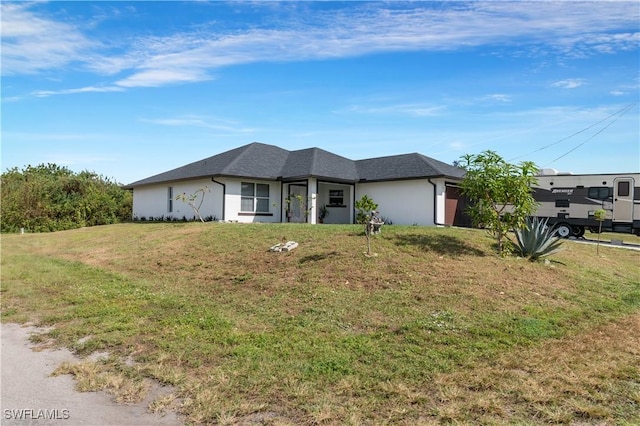 2918 12th St SW, Lehigh Acres, FL 33976 - view of front facade featuring a front yard, a garage, roof with shingles, and stucco siding
