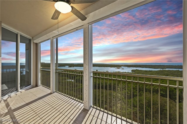 unfurnished sunroom featuring a water view and ceiling fan