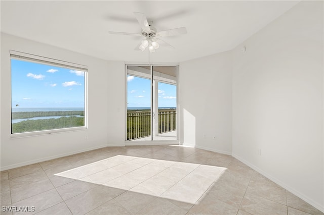 1001 Arbor Lake Dr Unit 1003, Naples, FL 34110 - empty room with light tile patterned floors, a ceiling fan, a water view, and baseboards