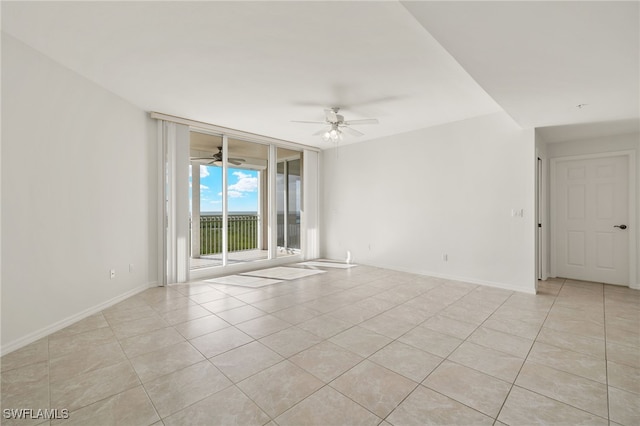 1001 Arbor Lake Dr Unit 1003, Naples, FL 34110 - empty room featuring light tile patterned flooring, a wall of windows, a ceiling fan, and baseboards