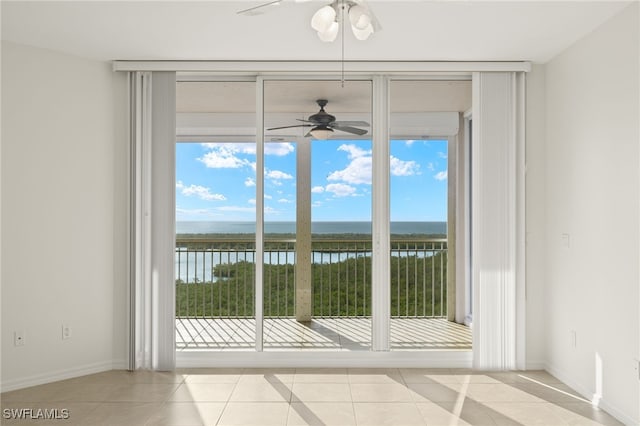 doorway featuring a wall of windows, light tile patterned flooring, ceiling fan, and a water view