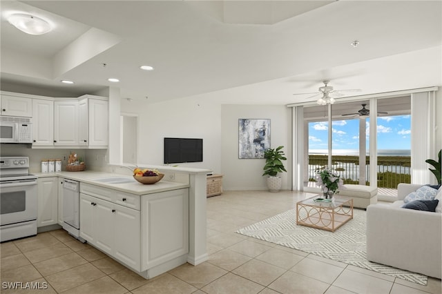 kitchen with light tile patterned flooring, sink, white cabinets, kitchen peninsula, and white appliances