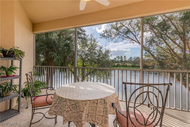 sunroom featuring ceiling fan and a water view