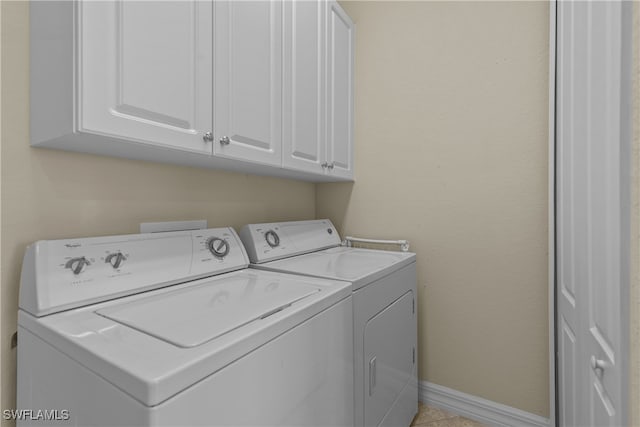 clothes washing area featuring cabinets, separate washer and dryer, and light tile patterned floors