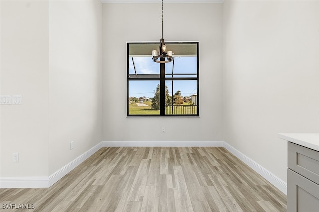 unfurnished dining area featuring light hardwood / wood-style flooring and an inviting chandelier