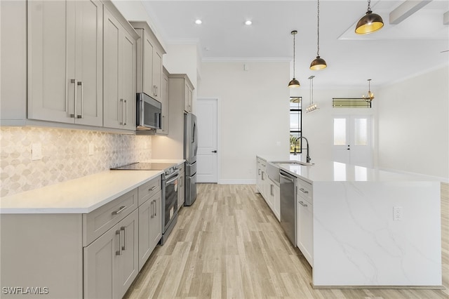 kitchen featuring ornamental molding, sink, pendant lighting, appliances with stainless steel finishes, and light hardwood / wood-style floors