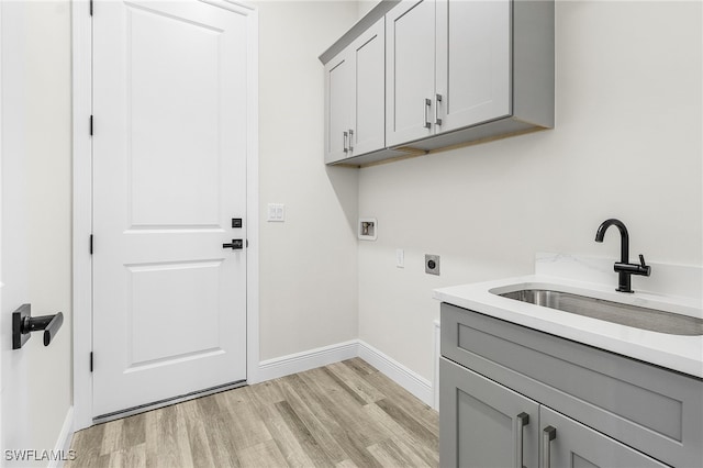 laundry room with cabinets, light hardwood / wood-style flooring, hookup for a washing machine, hookup for an electric dryer, and sink