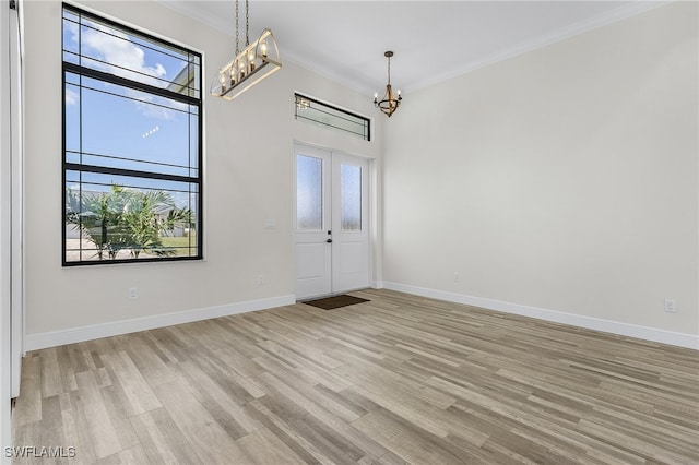 entrance foyer with crown molding, light hardwood / wood-style floors, a notable chandelier, and a healthy amount of sunlight