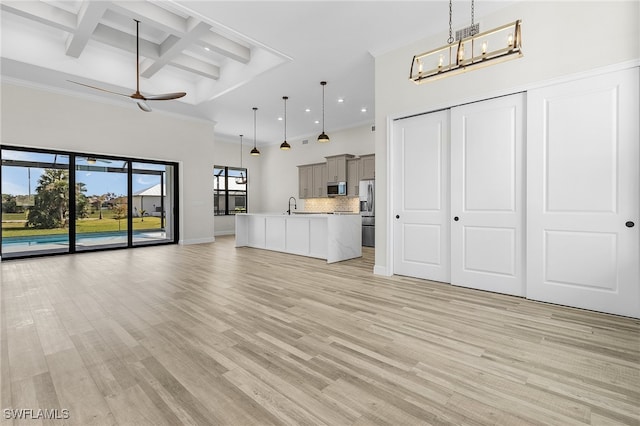 unfurnished living room featuring light hardwood / wood-style flooring, sink, coffered ceiling, and ceiling fan