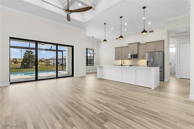 kitchen featuring a center island with sink, appliances with stainless steel finishes, light hardwood / wood-style flooring, gray cabinetry, and decorative light fixtures