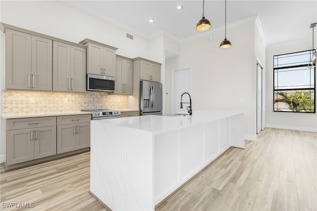 kitchen featuring sink, appliances with stainless steel finishes, light hardwood / wood-style flooring, and pendant lighting