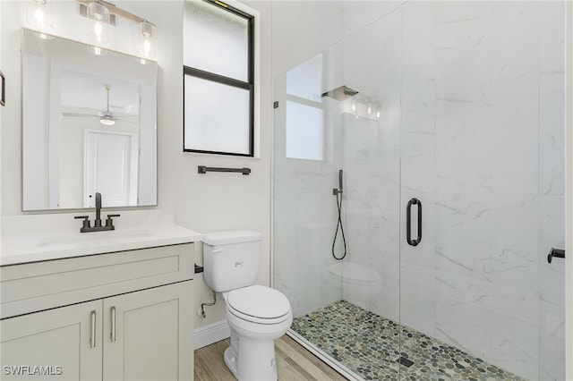 bathroom with ceiling fan, a shower with door, wood-type flooring, toilet, and vanity