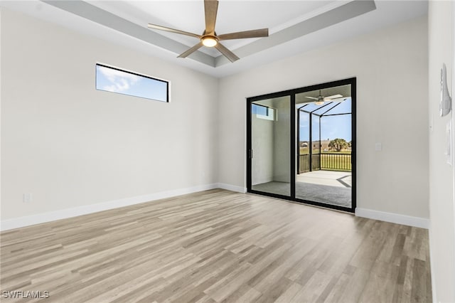 unfurnished room featuring ceiling fan, a raised ceiling, ornamental molding, and light wood-type flooring