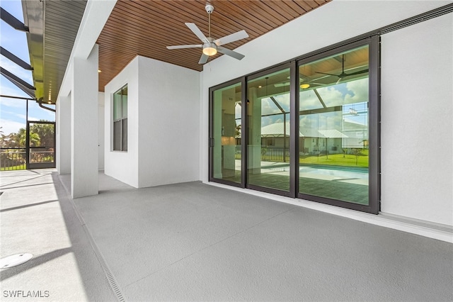 view of patio with ceiling fan and glass enclosure