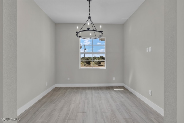 unfurnished dining area featuring light hardwood / wood-style flooring and a chandelier