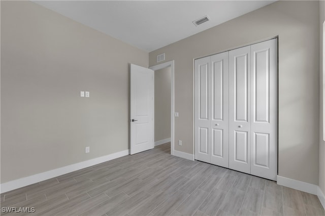 unfurnished bedroom with a closet and light hardwood / wood-style flooring