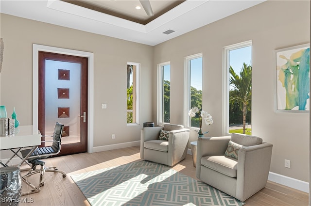 living area featuring a tray ceiling and light wood-type flooring