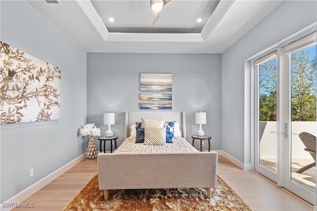 bedroom featuring ceiling fan, a tray ceiling, light wood-type flooring, access to exterior, and french doors