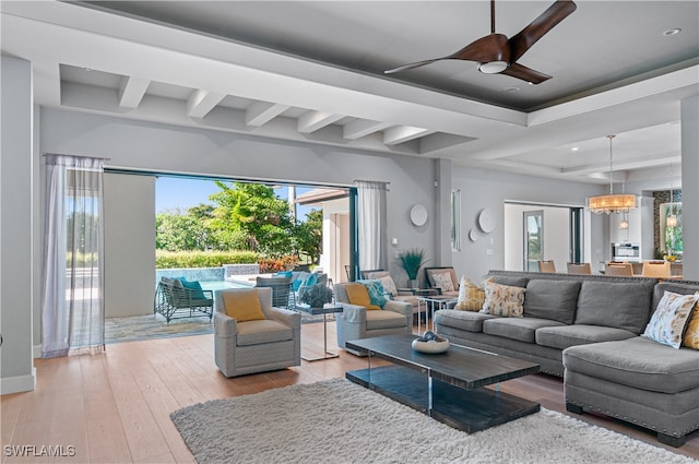 living room with ceiling fan, light wood-type flooring, beamed ceiling, and a healthy amount of sunlight