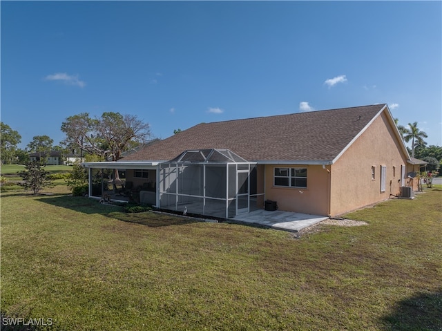 rear view of property featuring central AC unit, a yard, a patio, and glass enclosure