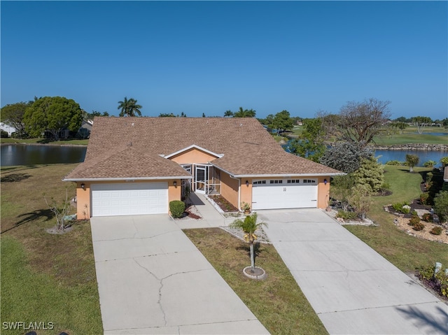 ranch-style home with a front yard, a garage, and a water view