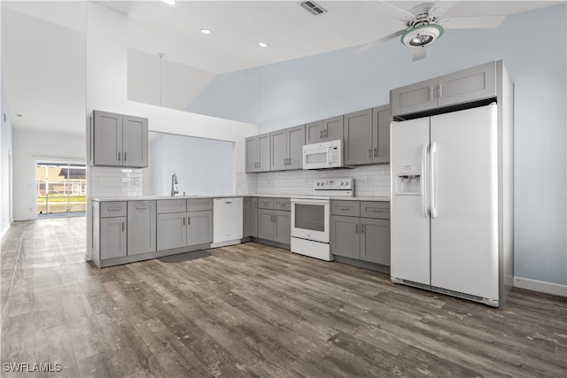 kitchen featuring white appliances, dark hardwood / wood-style floors, high vaulted ceiling, and gray cabinetry