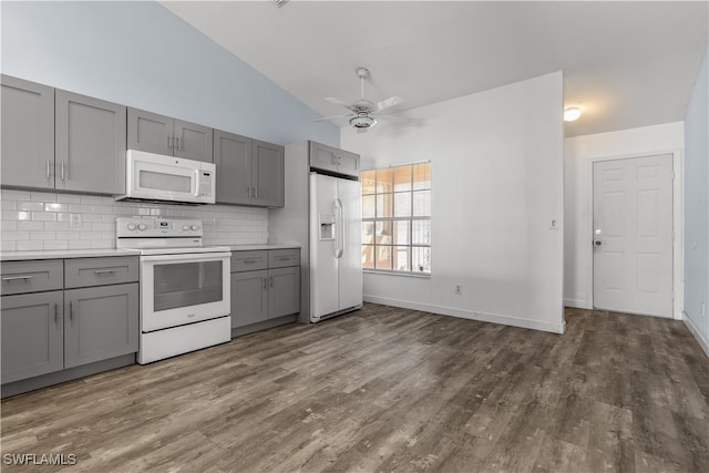 kitchen featuring white appliances, gray cabinetry, dark hardwood / wood-style flooring, lofted ceiling, and decorative backsplash