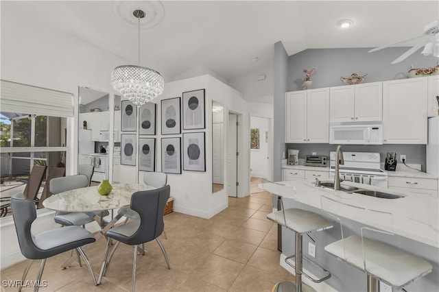 kitchen with light stone countertops, sink, hanging light fixtures, lofted ceiling, and white appliances