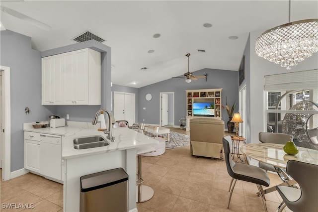 kitchen with pendant lighting, ceiling fan with notable chandelier, sink, vaulted ceiling, and white cabinetry