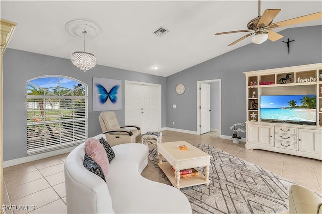 living room featuring ceiling fan with notable chandelier, light tile patterned floors, and lofted ceiling