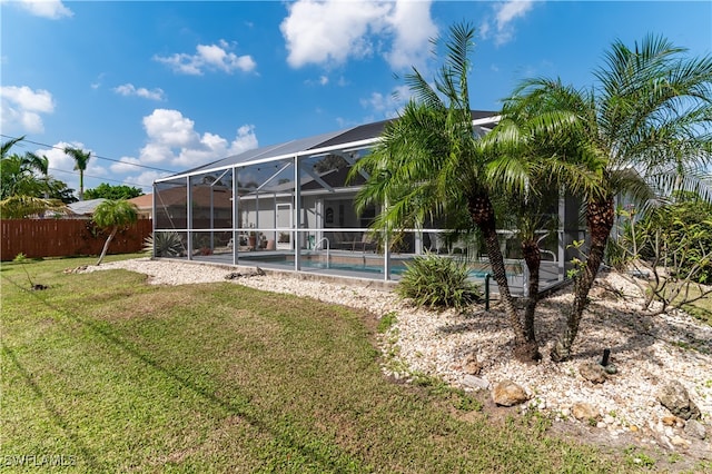 rear view of property with a fenced in pool, a lanai, and a lawn