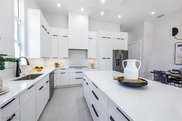 kitchen featuring light stone counters, sink, white cabinets, and appliances with stainless steel finishes