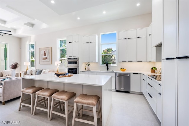 kitchen featuring a breakfast bar, sink, white cabinetry, a center island, and appliances with stainless steel finishes