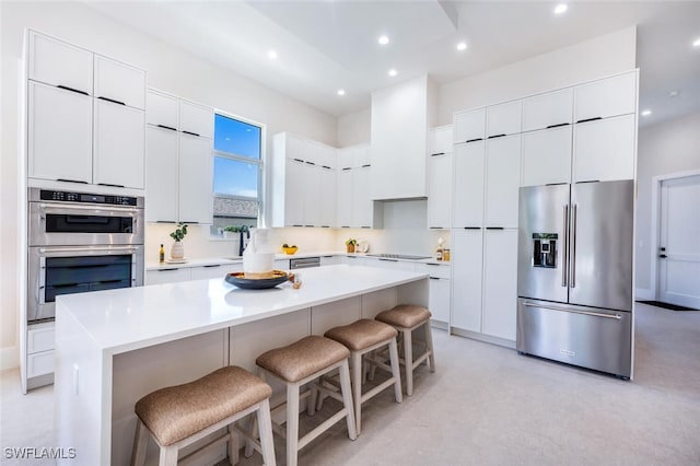 kitchen featuring a center island, a breakfast bar, white cabinets, and appliances with stainless steel finishes