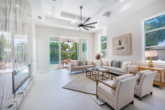 living room with a towering ceiling, ceiling fan, and a tray ceiling