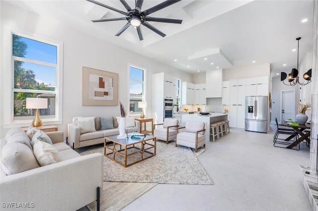 living room with a towering ceiling and ceiling fan with notable chandelier