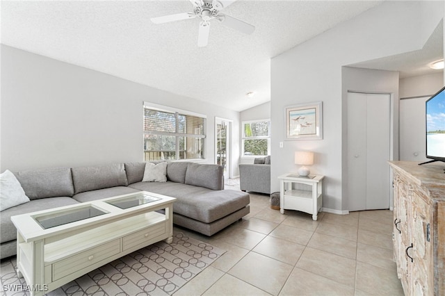 tiled living room featuring ceiling fan, a textured ceiling, lofted ceiling, and a wealth of natural light