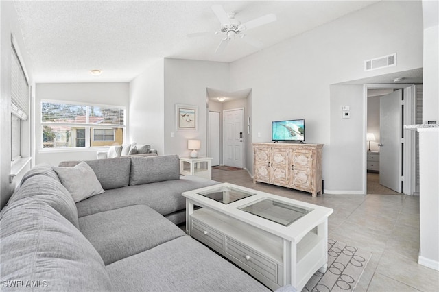 tiled living room with ceiling fan, high vaulted ceiling, and a textured ceiling