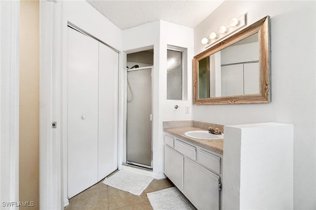 bathroom with vanity, tile patterned flooring, a textured ceiling, and an enclosed shower