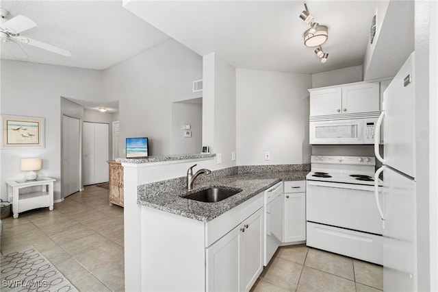 kitchen with kitchen peninsula, white cabinets, dark stone counters, sink, and white appliances