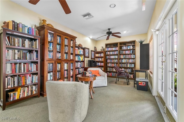 living area with light carpet and ceiling fan