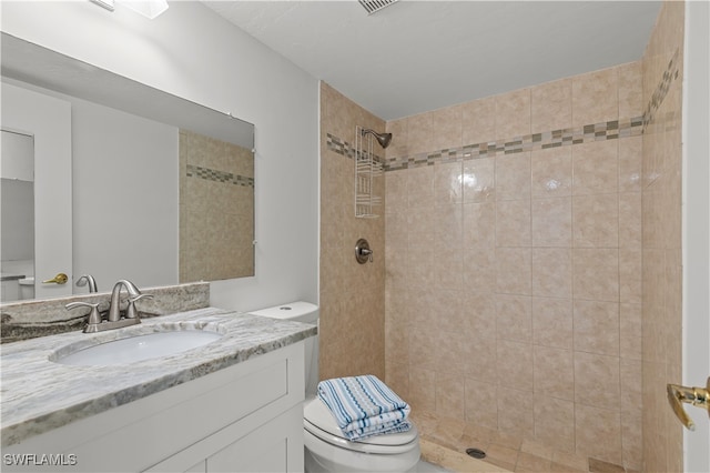 bathroom with toilet, vanity, and a tile shower