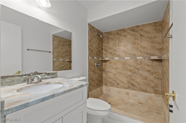 bathroom with tiled shower, vanity, and toilet