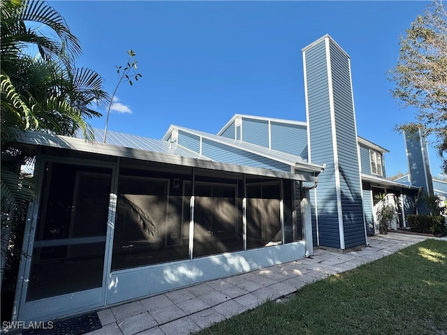 rear view of house with a lawn and a sunroom