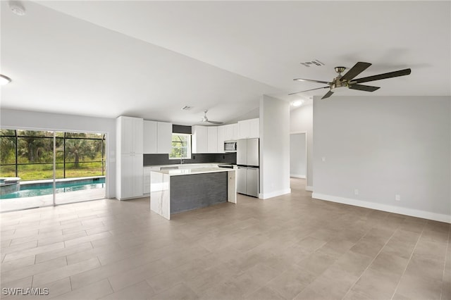 kitchen with white cabinets, stainless steel appliances, a center island, and vaulted ceiling