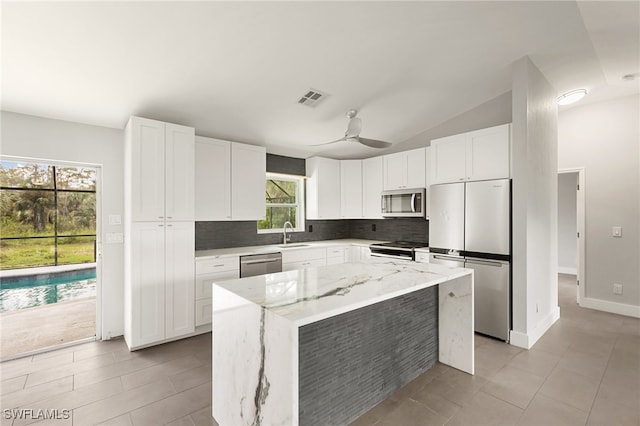 kitchen featuring white cabinetry, light stone countertops, a healthy amount of sunlight, and stainless steel appliances