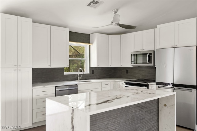 kitchen with white cabinetry, light stone counters, appliances with stainless steel finishes, and a center island