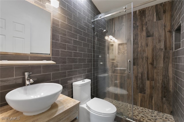 bathroom featuring tile walls, vanity, toilet, and a shower with door